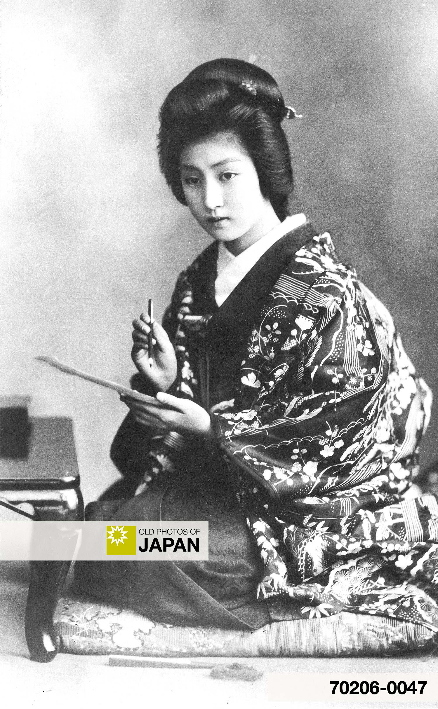 A young Japanese woman in kimono and traditional hairstyle is writing a 